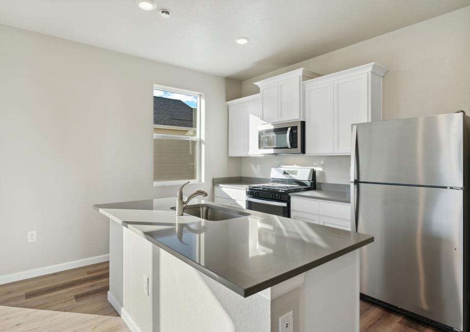 The kitchen has stainless steel appliances and plank flooring.