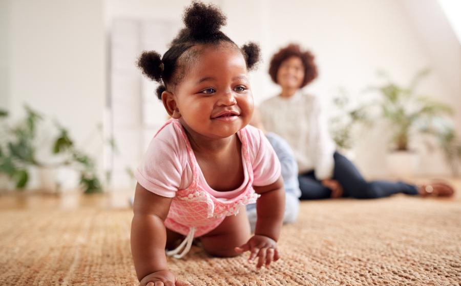 Toddler girl walking from dad to mom in the living room.