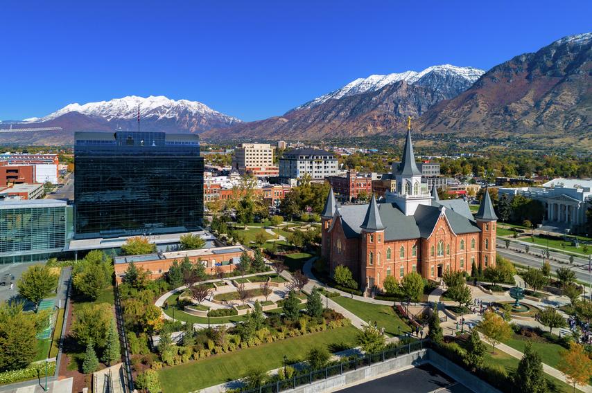 Aerial of downtown Provo, Utah showing the Provo City Center Temple and One Nu Skin Plaza, with the snow capped Wasatch Mountain Range in the background.