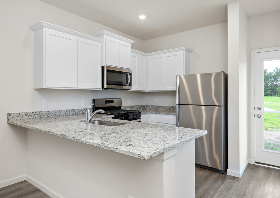 The kitchen has stainless steel appliances and plank flooring.