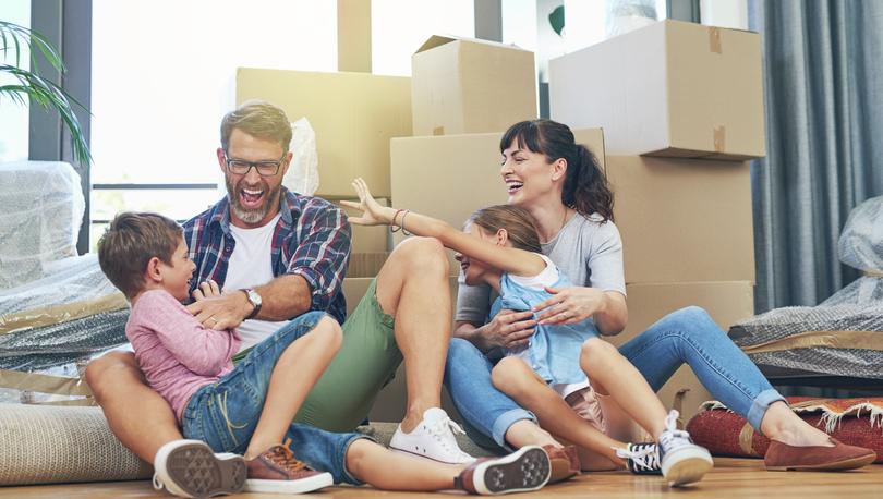 Family sitting on the floor surrounded by moving boxes.