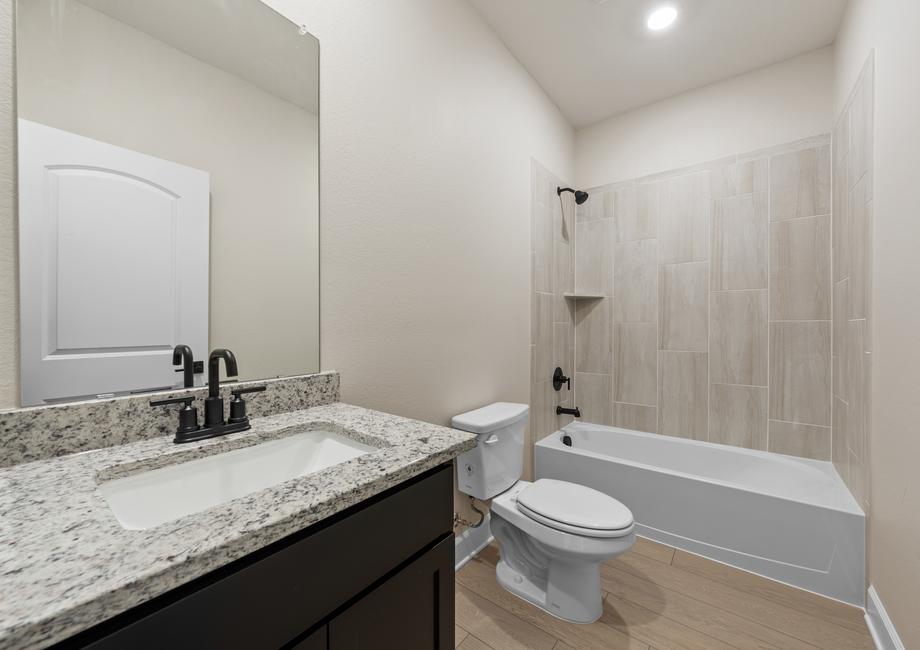 The secondary bathroom has a spacious vanity area and a tiled shower-tub combo.