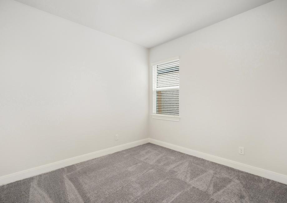 Guest bedroom with recessed lighting and a window, creating a bright space.