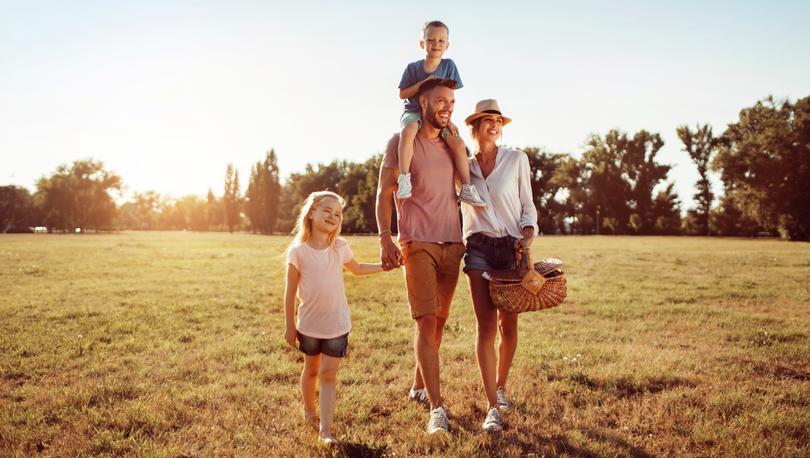 Family walking through grass with a picnic basket.