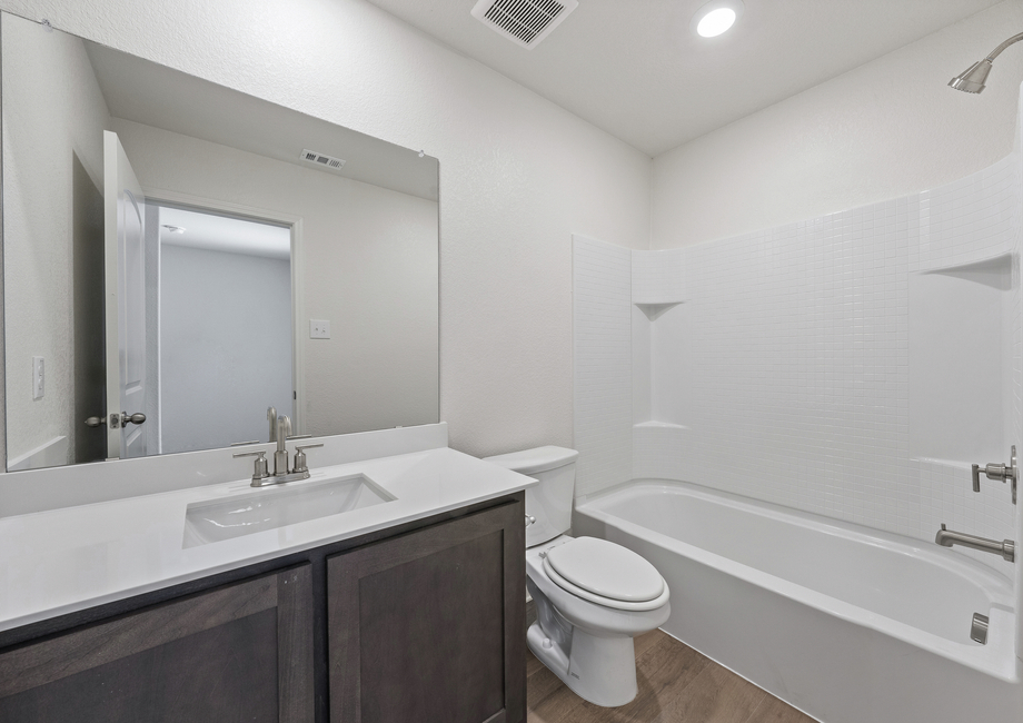 The secondary bathroom has a sprawling vanity space and a shower-tub combo.