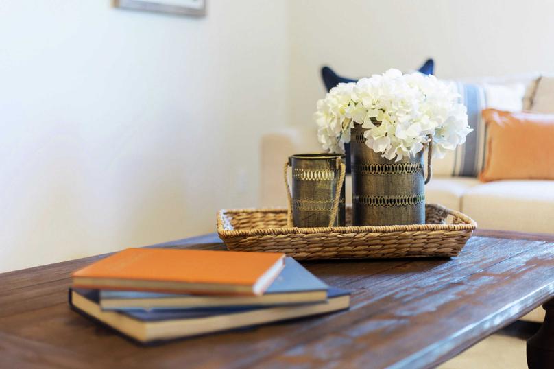 Staged model home with books, woven tray, and white flowers in a coffee can on a wooden table