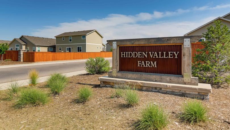 Hidden Valley Farms community entrance sign with plants and rocks around it.