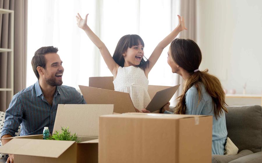 Family unpacking boxes, happy girl with arms in air