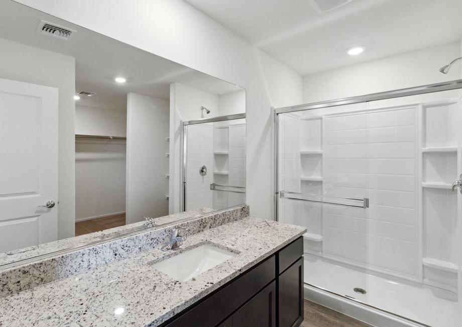 An en-suite master bathroom features a large walk-in shower and expansive counter space.