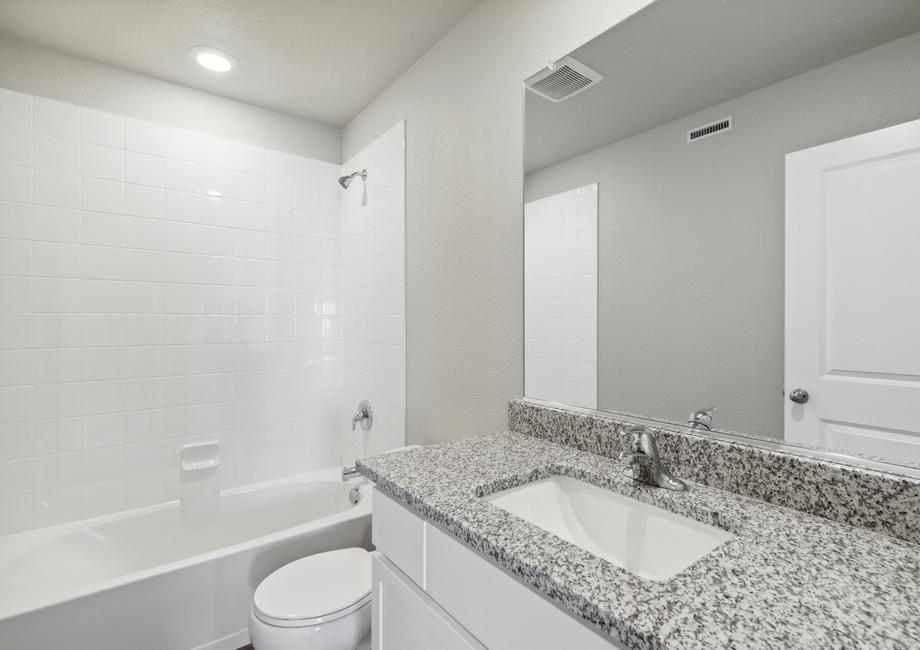 The secondary bathroom has a large vanity space and a shower-tub combo.