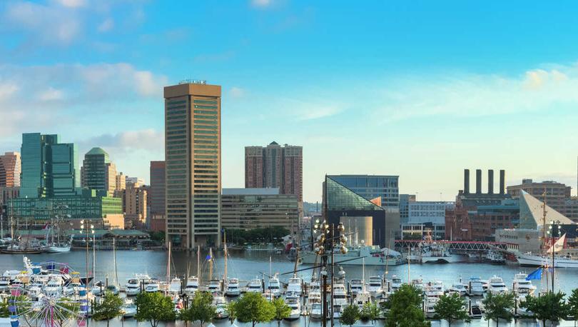 Baltimore, Maryland Inner Harbor picture taken at morning showing multiple belts in the marina, calm waters, and tall skyscrapers in the distance