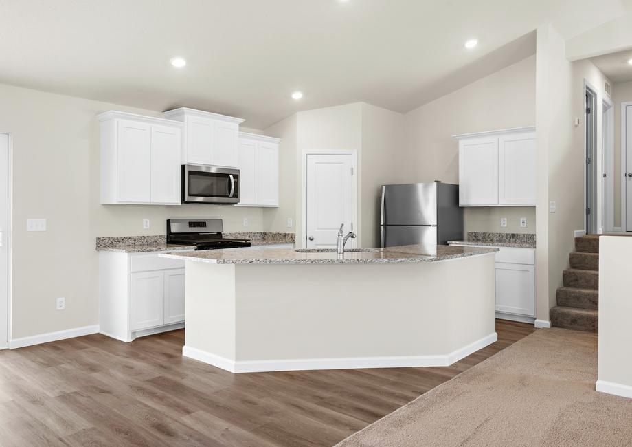 The kitchen has stainless steel appliances and plank flooring.