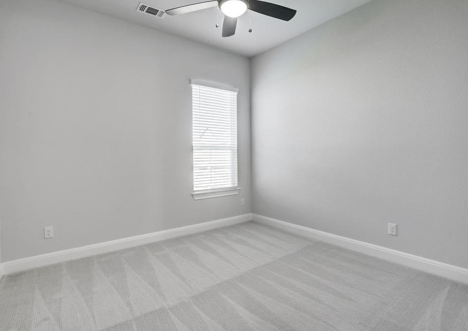 Guest bedroom with a ceiling fan, window, and soft carpet.