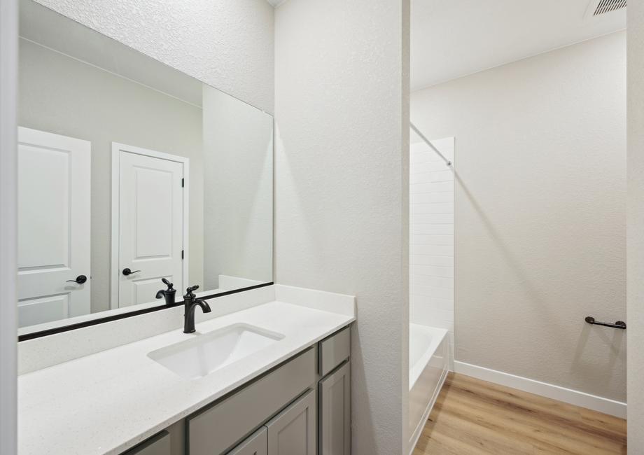 The secondary bathroom has a large vanity space and a shower-tub combo.