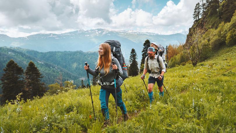 Young couple with their child hiking in the mountains during the summer.