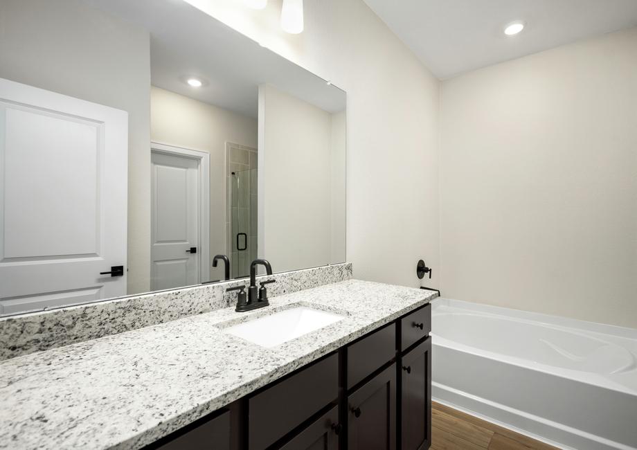 The modern master bathroom has lots of counterspace and a tub