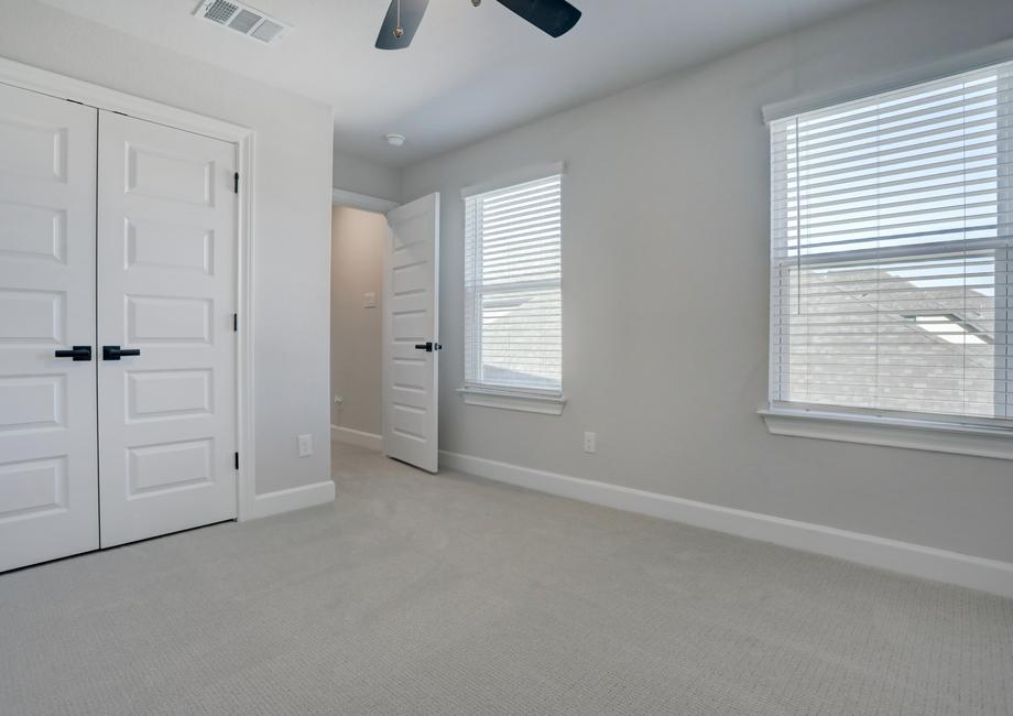 Guest bedroom with a large closet, two windows, and a ceiling fan.