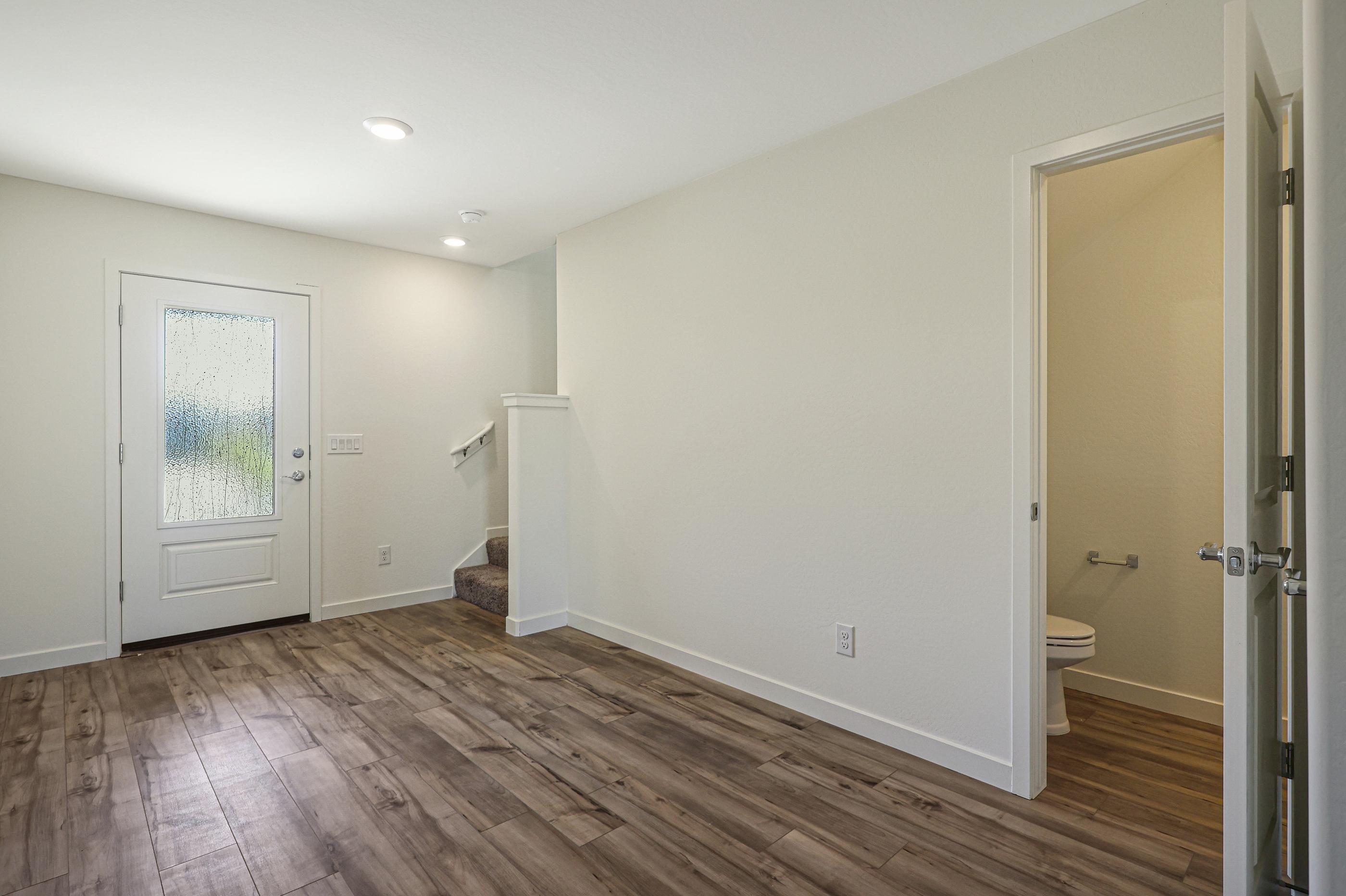 The entryway offers a spacious foyer with access to the additional bathroom and staircase.