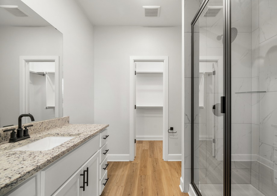 The master bathroom has a large vanity space and a glass, walk-in shower.