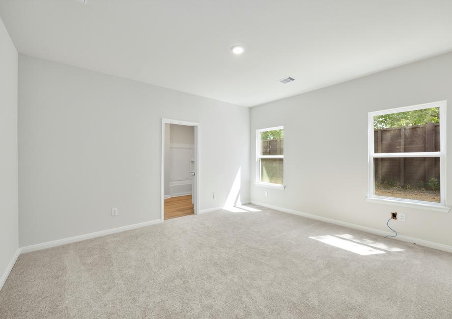 The master bedroom has large windows and carpet. 