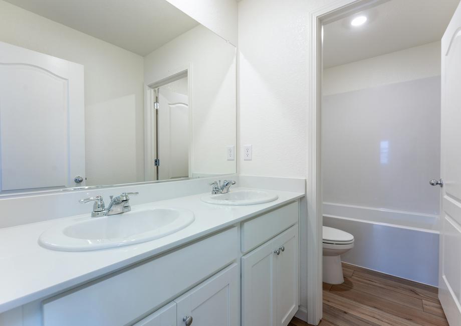 The secondary bathroom has a dual sink vanity and tub/shower combo.