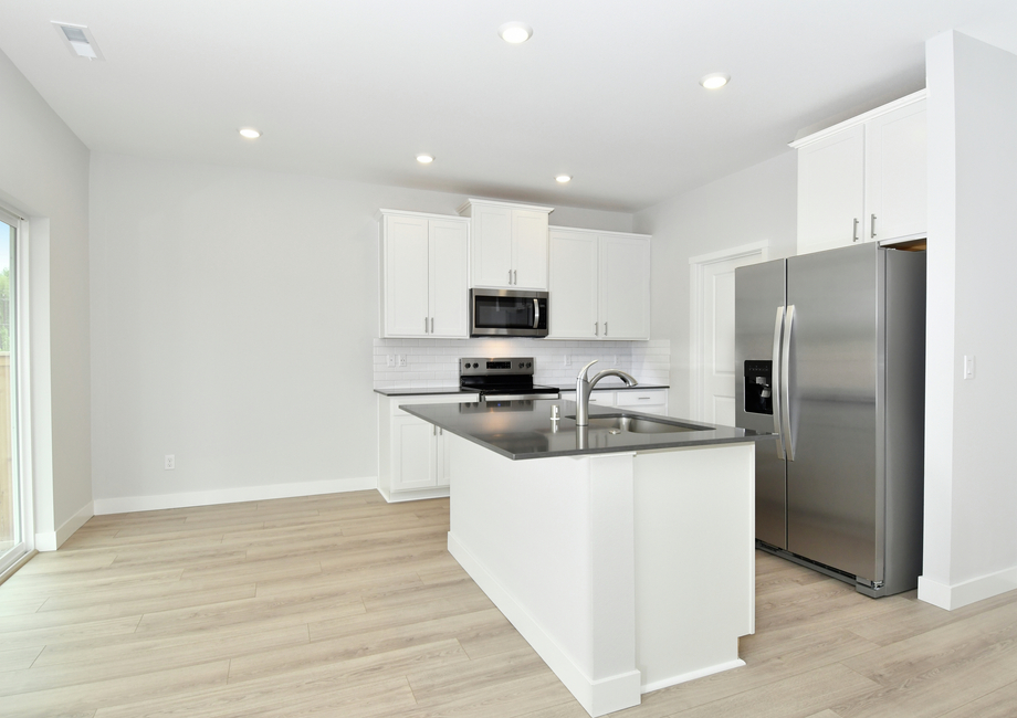 The kitchen has stainless steel appliances and plank flooring.