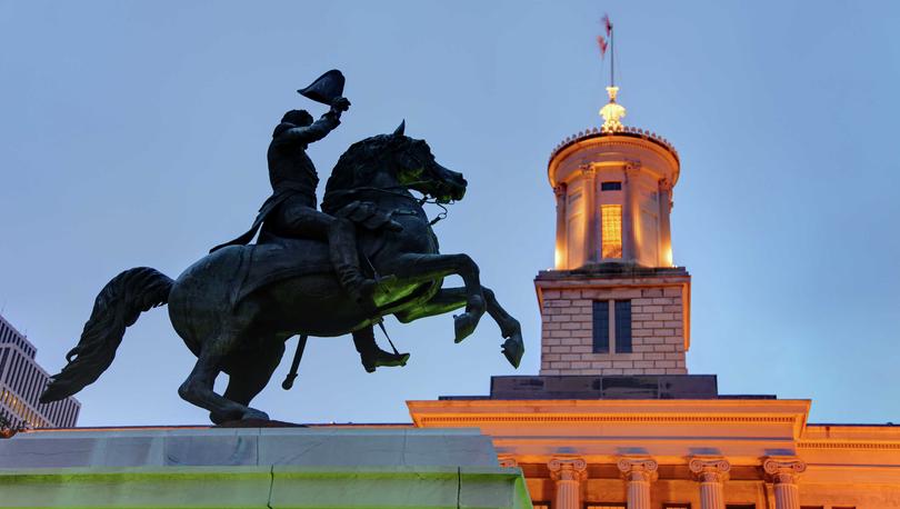 Nashville, Tennessee State Capitol building showing statue of Andrew Jackson, tall building pillars, and lit cupola