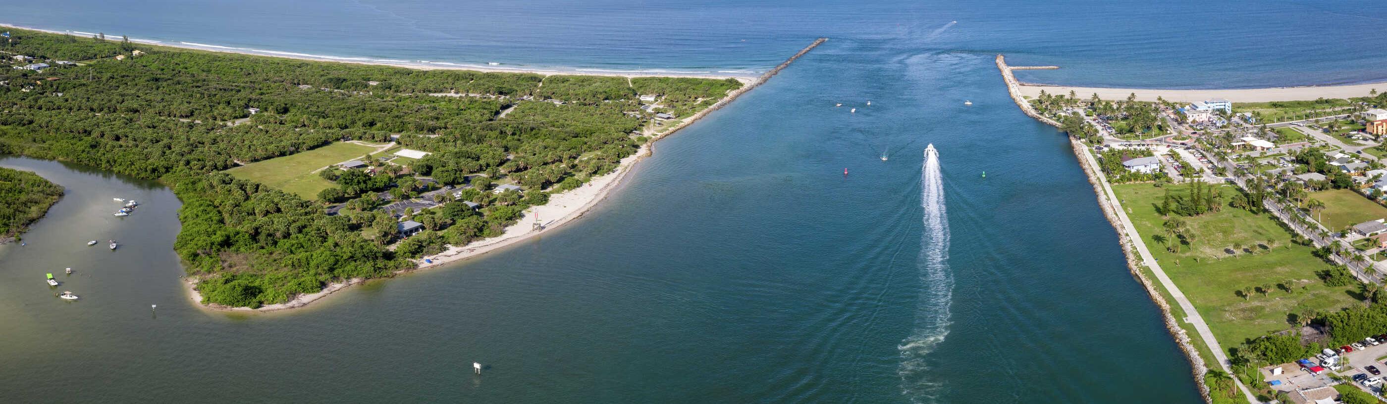 Fort Pierce, Florida beach inlet with boats moving through the water, green parklands to the left, and condos to the right