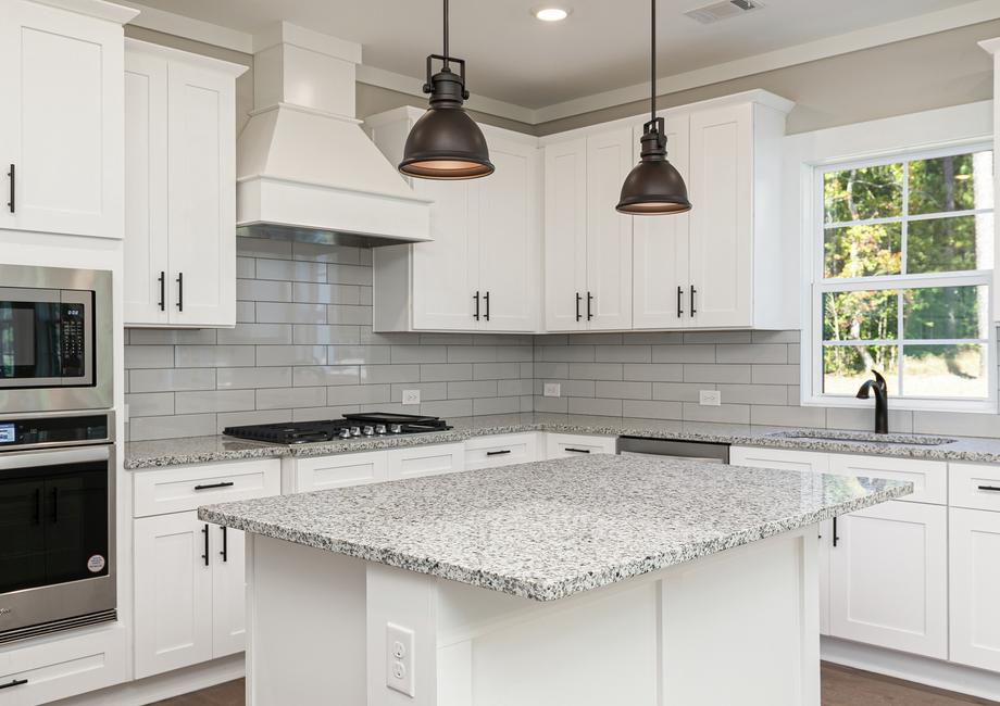Kitchen with a larg granite island and white cabinets.