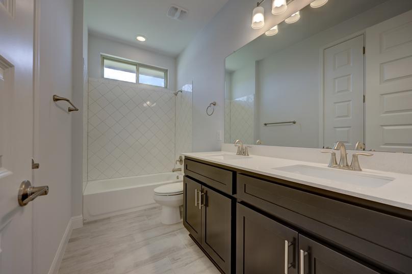 Guest bathroom with a double-sink vanity and a dual shower and tub that provides conveniences to all guests.