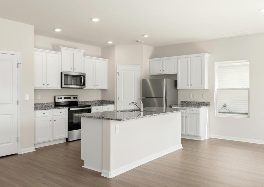 Kitchen with granite countertops, white cabinets with hardware, stainless steel appliances and vinyl flooring. 