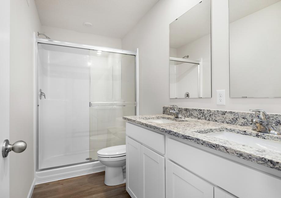 The master bathroom has a step in shower and dual sink vanity.