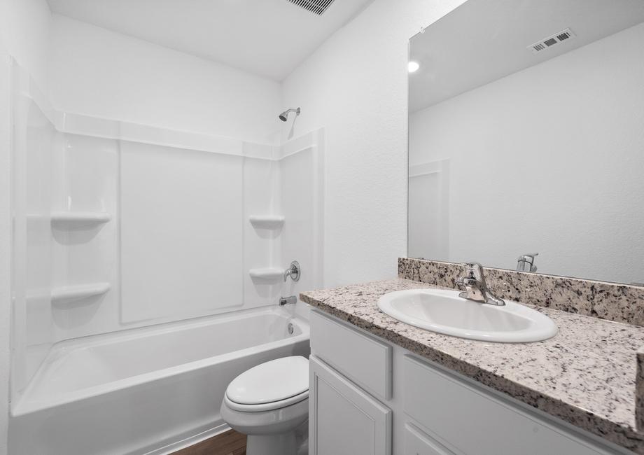 Secondary bathroom with white cabinets and granite countertops.