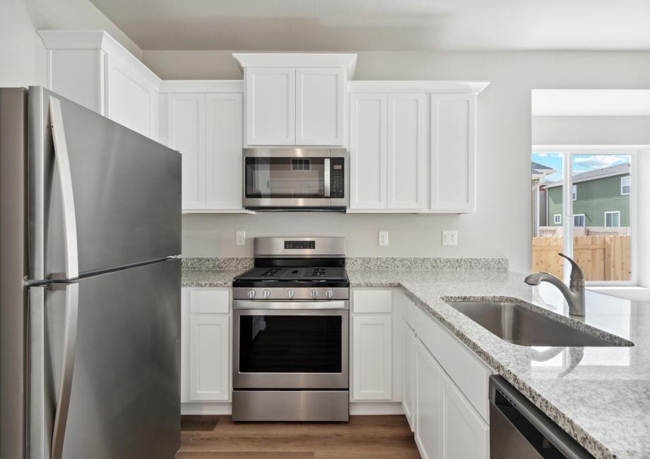 The kitchen has stainless steel appliances and plank flooring.