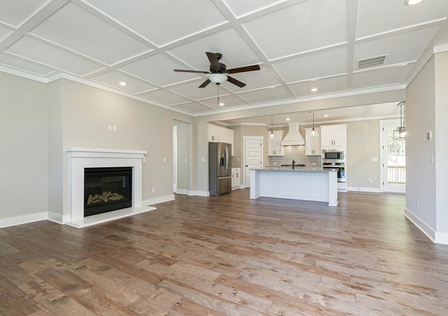 Angled view of the living room with a fireplace and the kitchen.