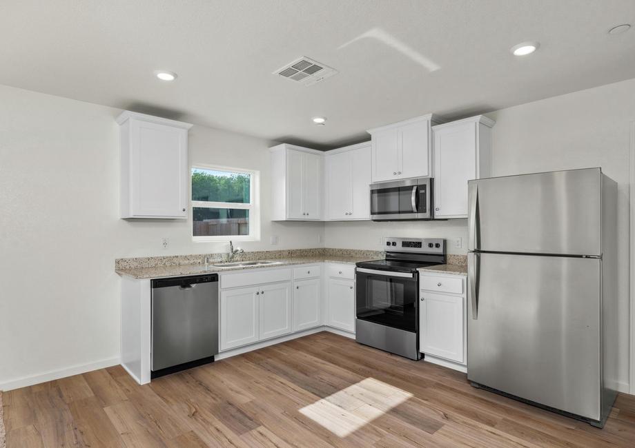 The kitchen has stainless steel appliances and plank flooring.