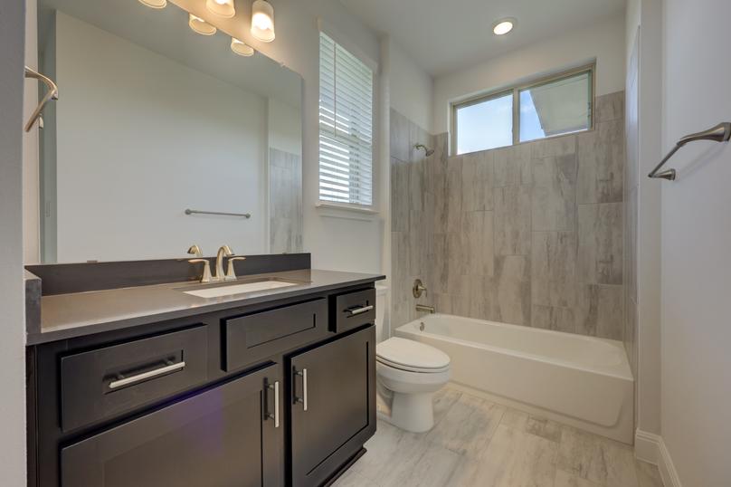 Secondary bathroom with a tile-lined dual shower and tub to meet the needs of your household.