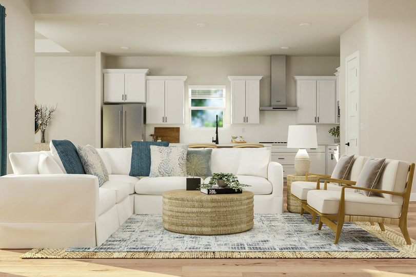 Rendering of the living room showing a
  white sectional couch, coffee table, designer rug, coffee table and two arm
  chairs with a view of the kitchen in the background and light wood look
  flooring throughout.