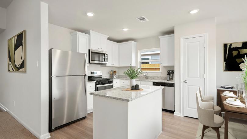 The staged kitchen has beautiful stainless steel appliances and plank flooring.