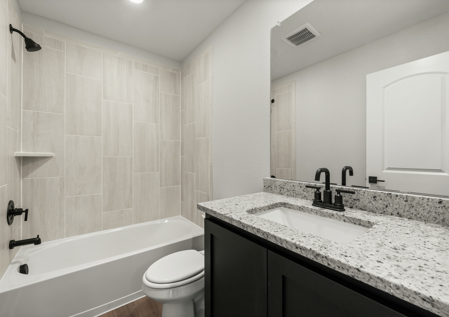 The secondary bathroom has a spacious vanity and a tiled shower-tub combo.