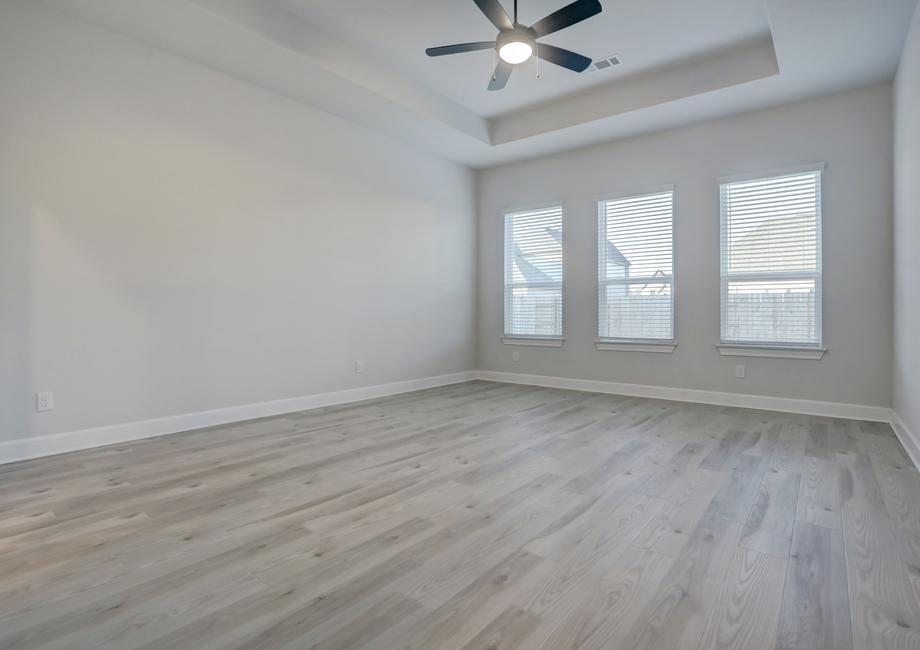 Master bedroom with three large windows that create a bright, open room.