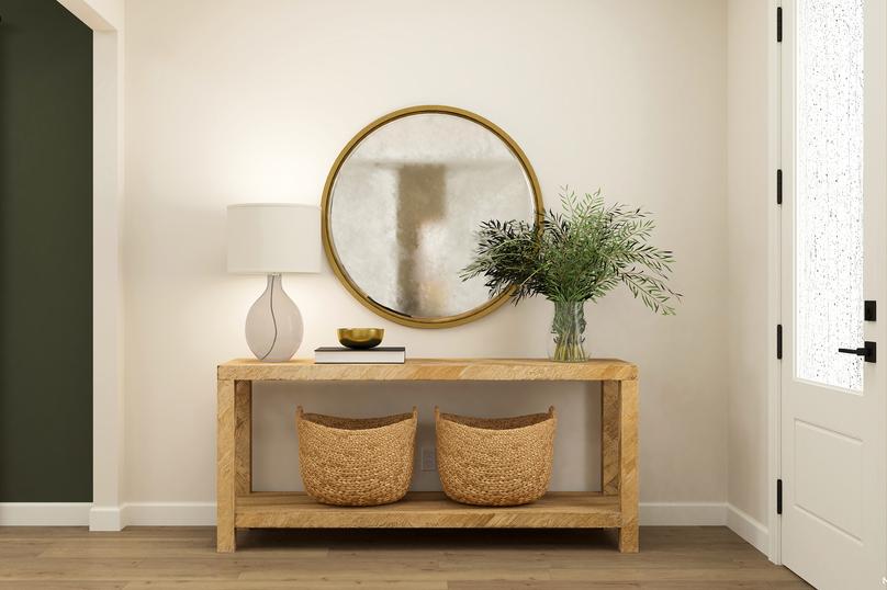 Rendering of the entryway with 3/4 lite
  door and wood-look flooring. The space is decorated with a console table,
  decorative baskets and a large, round mirror.