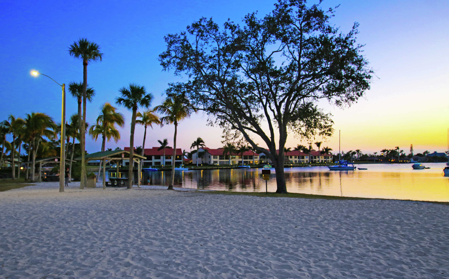 Cape Coral, Florida beach park with white sands, palm trees, and calm waters at sunset