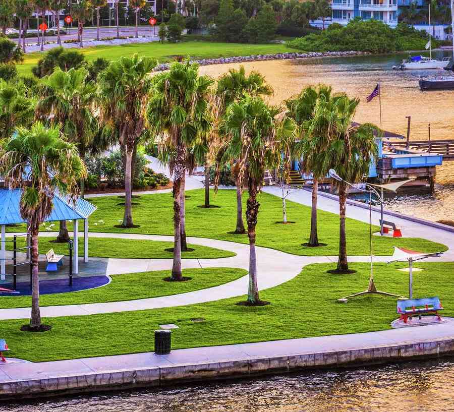 Sarasota, Florida skyline at sunset showing park with walkways, bay with boats in the water, and condos in the background