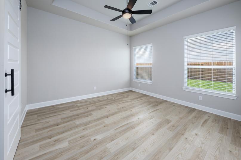The large master bedroom has a ceiling fan and a sliding door that opens to the bathroom.