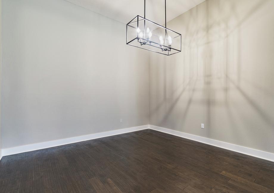 Formal dining room with wood flooring and a black iron chandelier. 