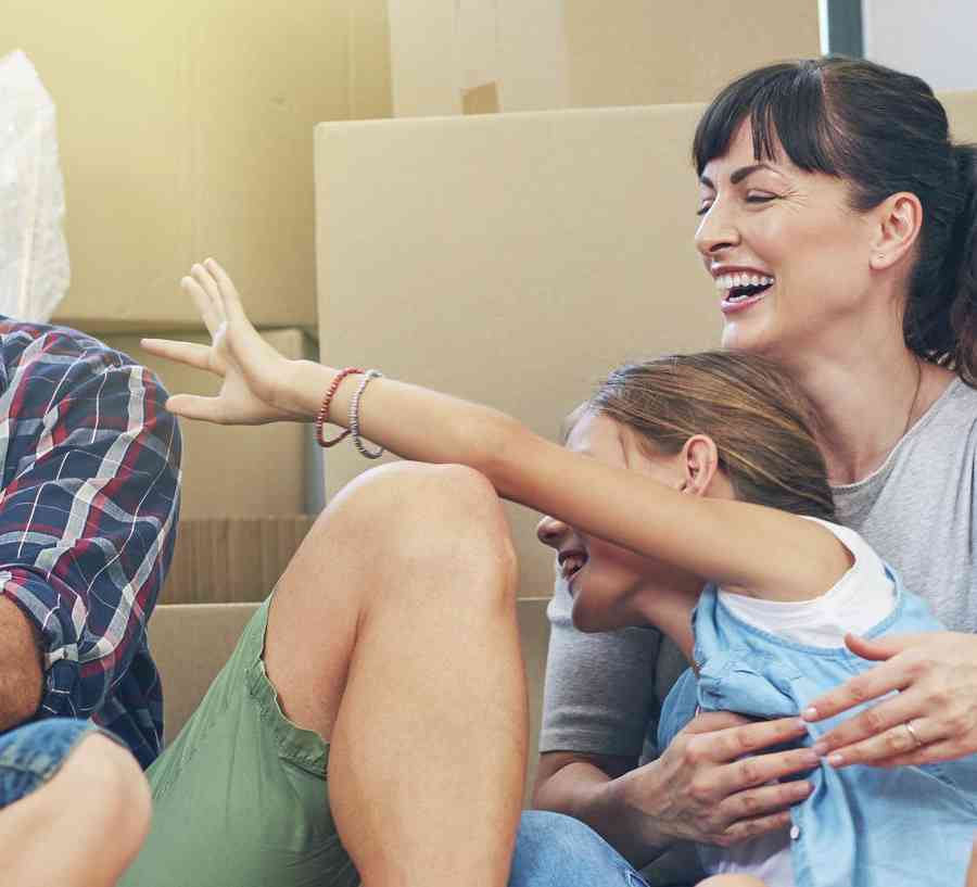 Family sitting on the floor surrounded by moving boxes.