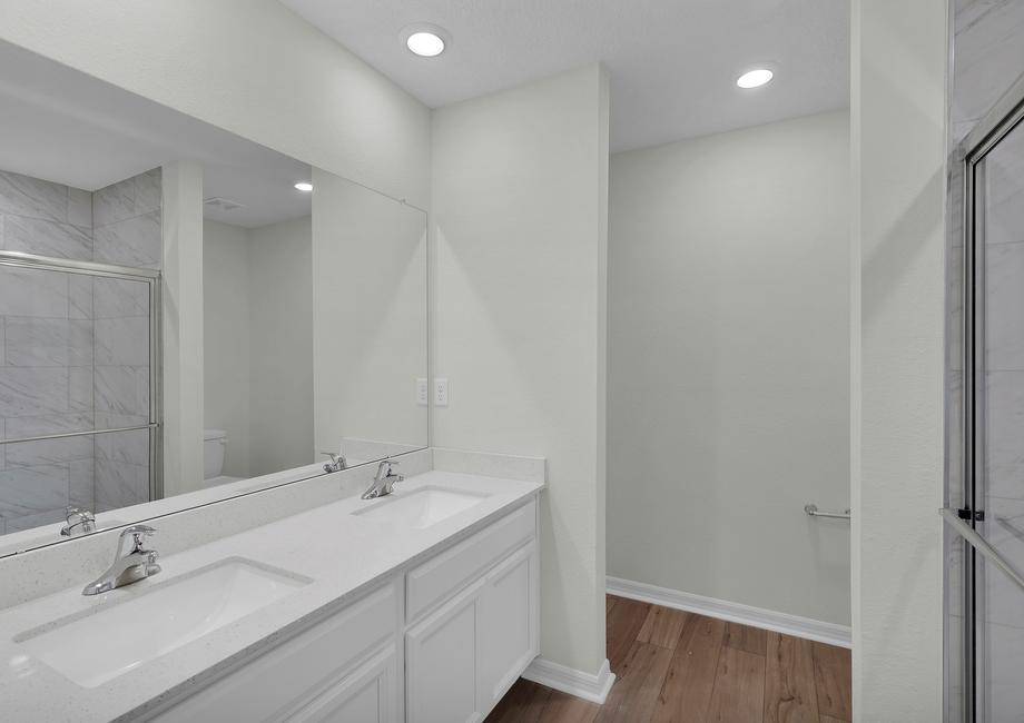 This bathroom has dual vanities and a glass-enclosed shower.