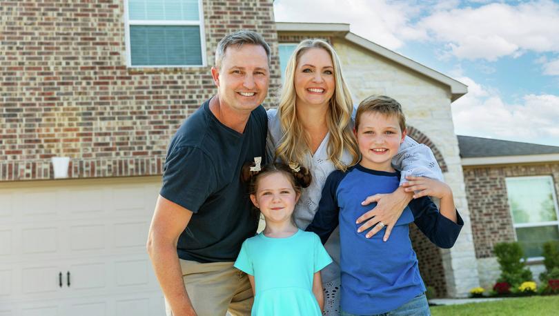 Family in front of a brick and stone house.