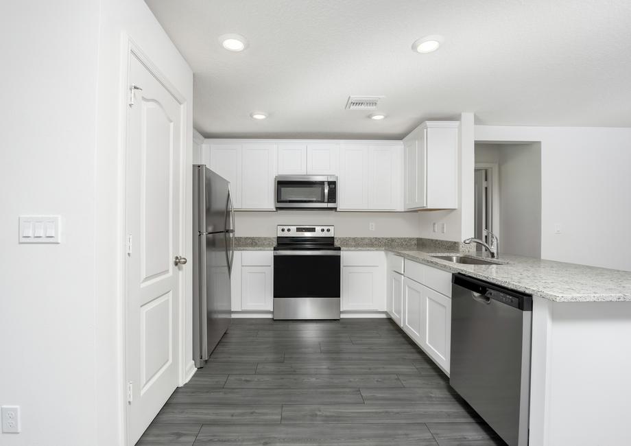 The kitchen has gorgeous granite countertops and white cabinets.